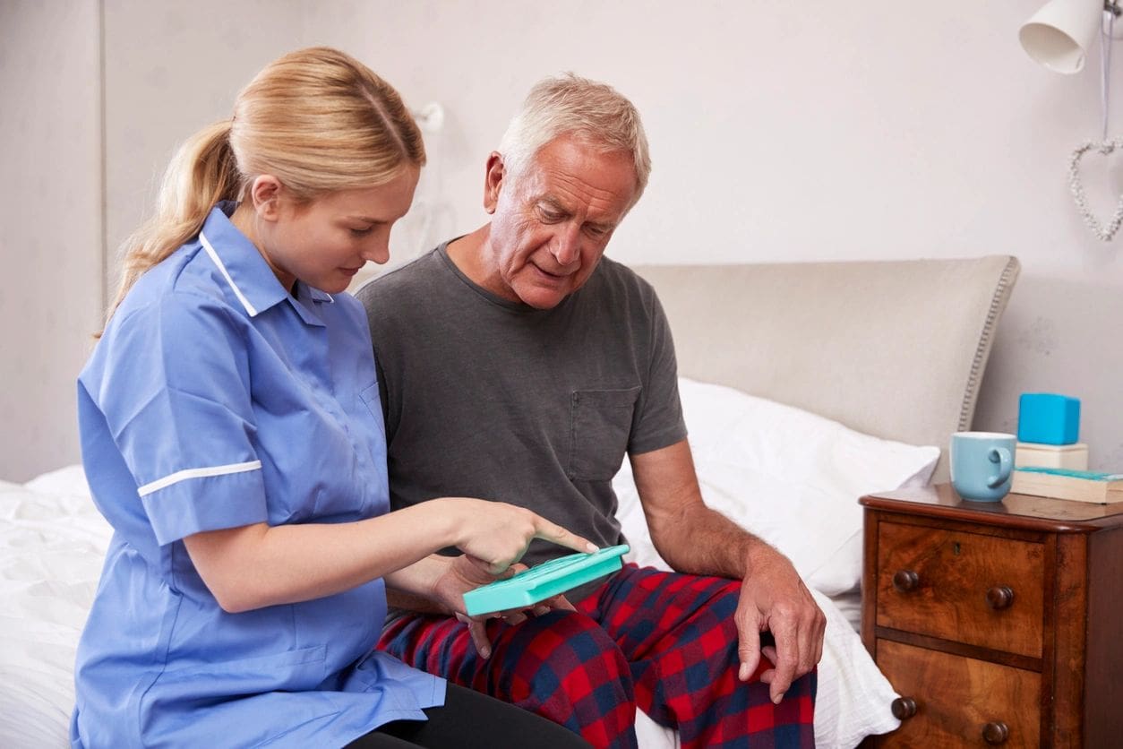 A nurse is helping an older man with his medical equipment.