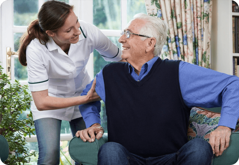 A woman helping an older man sit on the couch